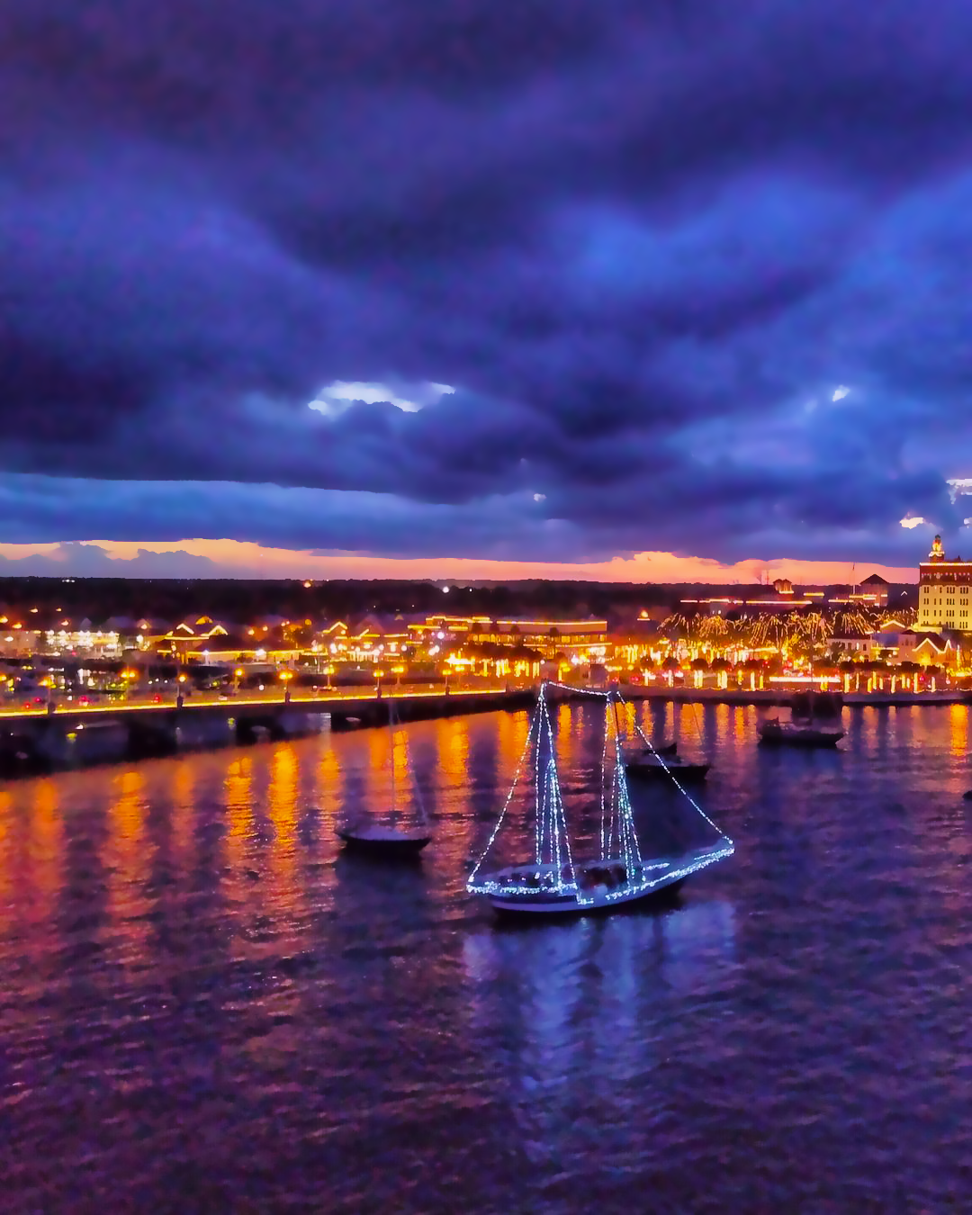 Schooner Freedom Nights of Lights, the sail boat lit up with St. Augustine in the background lit up